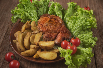 pork steak with fried potatoes on lettuce leaves with cherry tomatoes