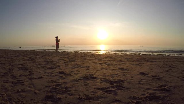 People taking photos on the beach during sunset