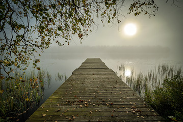 Foggy sunrise and wooden bridge in September