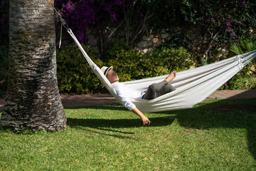 male relaxing in a hammock in the garden.