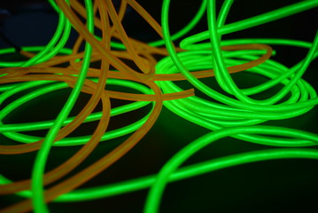 Bright luminous yellow and green, lime neon wires in different formats and layouts. An electroluminescent wire, a neon light guide, an ice tube are folded into different structures and shapes.