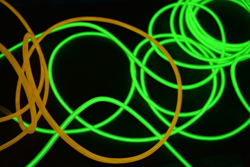 Bright luminous yellow and green, lime neon wires in different formats and layouts. An electroluminescent wire, a neon light guide, an ice tube are folded into different structures and shapes.