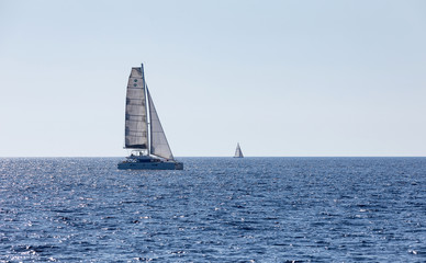 Fototapeta premium Sailboat on the horizon, blue sailboat on the sea. Concept for sport and vacation.