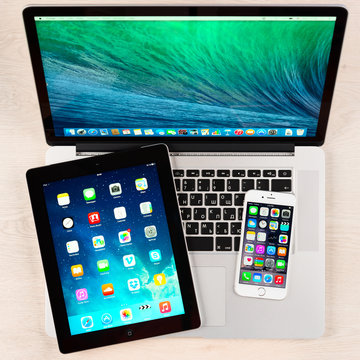 Apple IPhone, IPad And Macbook Pro Over Table. Apple Inc. Is An American Multinational Corporation That Designs, Develops, And Sells Consumer Electronics.