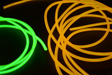 Bright luminous yellow and green, lime neon wires in different formats and layouts. An electroluminescent wire, a neon light guide, an ice tube are folded into different structures and shapes.