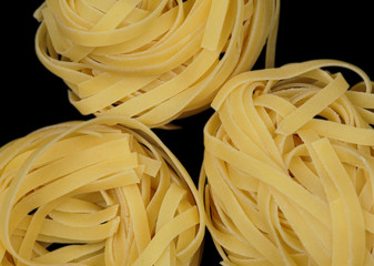 Closeup of a three italian tagliatelle isolated at black background