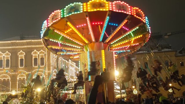 People have fun and celebrate New Year on Red Square, riding on a carousel beautiful colorful brightly glowing carousel decorated and arranged for winter holidays. Christmas fairy illuminated