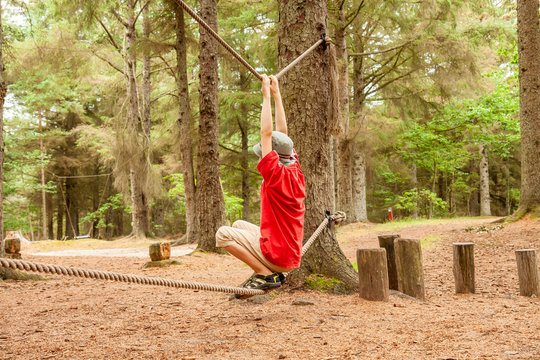 Teenager boy hanging between two ropes in the forest