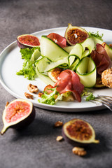 Green salad with figs on white plate and grey backgorund. Gourmet conception.