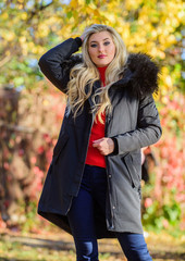 Girl in warm coat stand in park nature background defocused. Woman long blonde hair wear stylish outfit with parka. Create fall outfit to feel comfortable and pretty. Modern outfit for youth