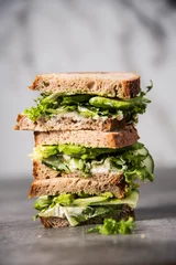 Zelfklevend Fotobehang Drie sandwiches op elkaar. Gelaagde rustieke broden met avocado en frisse salade op grijze achtergrond. © maram