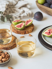 Two glasses of white wine, figs and almonds on a white background. Still life of holidays seasonal harvesting fall autumn concept. Copy space