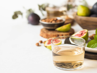 Glass of white wine, figs and almonds on a white background. Still life of holidays seasonal harvesting fall autumn concept. Copy space