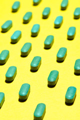 medicinal capsules, pills and tablets on yellow background. nutrition supplements, green vitamin pills