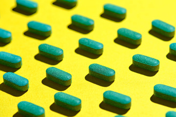 Obraz na płótnie Canvas medicinal capsules, pills and tablets on yellow background. nutrition supplements, green vitamin pills. Healthcare or medicament addiction concept. 