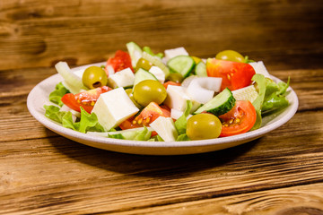 Ceramic plate with greek salad on wooden table