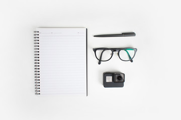 Top view of arrangement of notebooks, glasses, pen and camera. Isolated background.