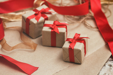 Set of gift boxes wrapped in craft paper and tie red satin ribbon. Christmas presents. Holiday mood. New year decor.