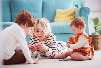 cute kids, siblings playing together on the floor at home