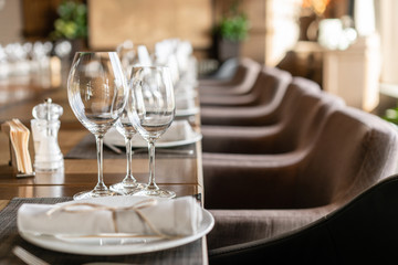 Wine glasses in the foreground. Wedding Banquet or gala dinner. The chairs and table for guests, served with cutlery and crockery.