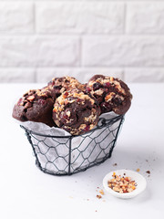 Chocolate muffins with nuts and cranberries on a light marble surface with copy space.