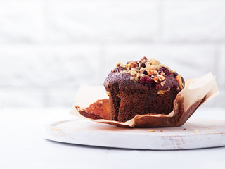 Close up Chocolate muffin with nuts and cranberries on a light marble surface with copy space.