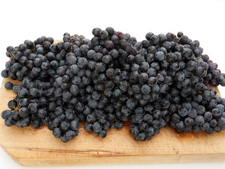 Blue concord style grapes on a cutting board on white