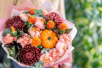 Autumn bouquet of mixed flowers in womans hands. The work of the florist at a flower shop. Fresh cut flower.