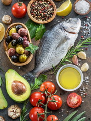 Raw dorado fish with spices and vegetables on the graphite board.