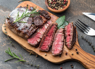 Medium rare Ribeye steak with herbs and a piece of butter on the wooden tray.