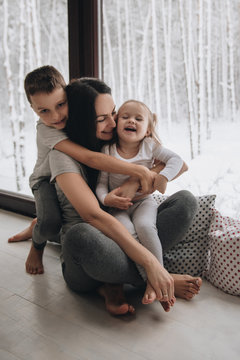 The family is sitting at the window and looking at the winter forest. Good New Year spirit. Morning in pajamas.