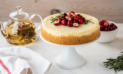 Classic New York Cheesecake with cranberry, rosemary and tea on White Concrete Background, copy spase. Tea and Cheesecake