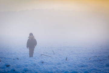On a walk, the child in the fog has poor visibility.