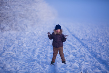Fototapeta na wymiar snowy landscape. on a walk in winter a boy of 7 years old has fun