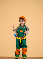 Builder. Kid playing with repair tools. Kid as construction worker. Repair concept. Little boy in helmet and tools. Little repairman. Tools for building. Little boy in builders uniform with toy tools.