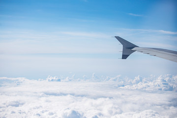 wing of airplane over cloudy blue sky in Europe on morning sun light, 