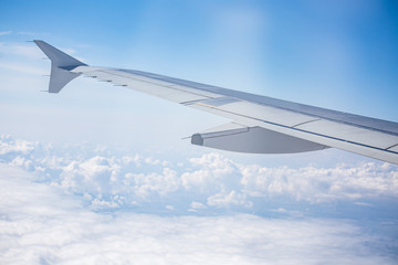 wing of airplane over cloudy blue sky in Europe on morning sun light, 