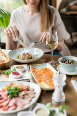 Portrait of a beautiful young elegant woman in the restaurant with a wine glass. Dinner and a variety of dishes on the table. Italian cuisine