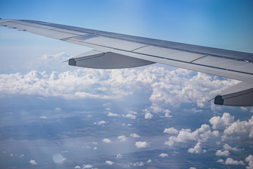 wing of airplane over cloudy blue sky in Europe on morning sun light, 