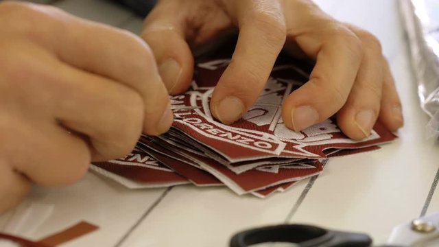 embroiderer hands work with precision on logos.embroidery workshop