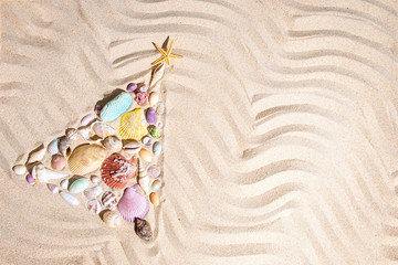 Fototapeta na wymiar Christmas tree made from shells and corals on beach sand with copy space, flat lay