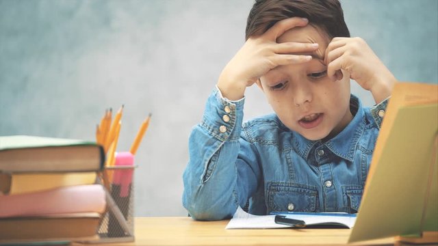 Young clever school kid in blue jeans t-shirt was writing and made a mistake. Now he doesn't know how to correct it.