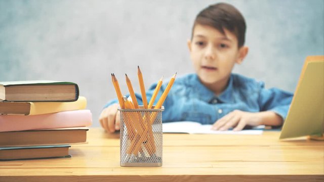 Creative little boy reaching a basket with pencils and drawing.