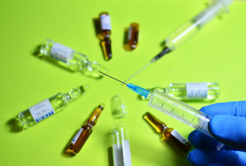 Doctor's hand in blue sterile glove holds a medical syringe with a needle with injection.  The concept of emergency care for patients with acute pain. Anesthesia with essential and essential medicines