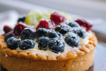 Tasty cake with fresh berries close up. Homemade tart with blueberries, raspberries and kiwi slices. Delicious dessert. Sweet breakfast concept. Pie with fruits and berries. Bakery concept.