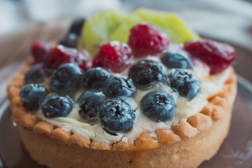 Tasty cake with fresh berries close up. Homemade tart with blueberries, raspberries and kiwi slices. Delicious dessert. Sweet breakfast concept. Pie with fruits and berries. Bakery concept.