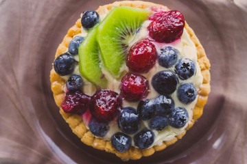 Tasty cake with fresh berries close up. Homemade tart with blueberries, raspberries and kiwi slices. Delicious dessert. Sweet breakfast concept. Pie with fruits and berries. Bakery concept.