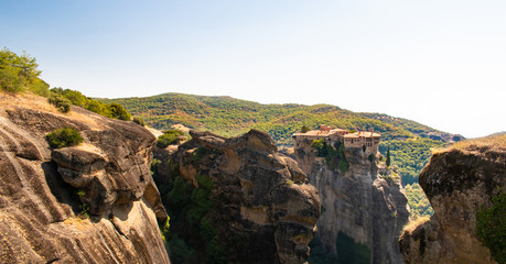 Fototapeta na wymiar Monastery Meteora Greece. Stunning panoramic landscape. View of mountains and green forest against epic blue sky with clouds. UNESCO heritage object.