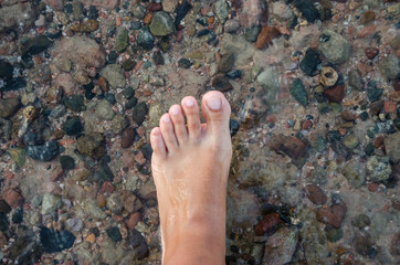 female foot on a background of sea water.