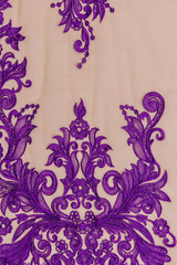 Texture lace fabric. lace on white background studio. thin fabric made of yarn or thread. a background image of ivory-colored lace cloth. Purple / violet lace on beige background.